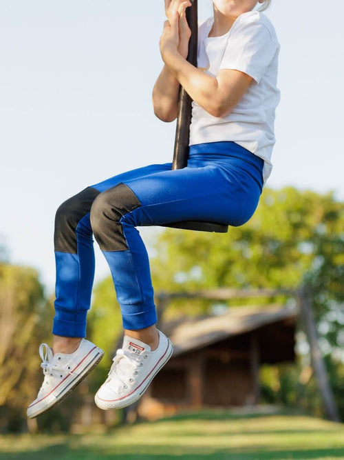 Kind auf der Seilschaukel in blauer Leggings mit verstärkten Knien